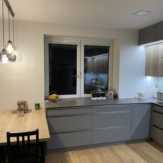Kuchyňská linka na míru šedé barvy doplněná dřevo dekorem Halifax Přírodní s kompaktní pracovní deskou a dřezem ze spodní montáží.