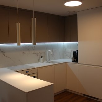 Kuchyňská linka na míru v bílém matném dekoru s kompaktní pracovní deskou a dřezem se spodní montáží.