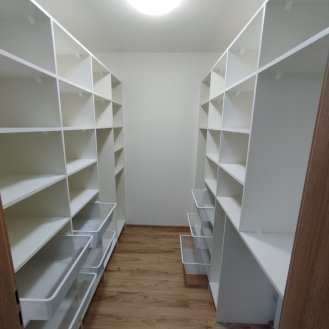 Nábytek na míru do šatny v bílém dekoru s výsuvnými koši na prádlo.