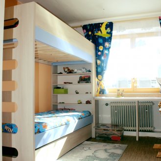 Patrová postel na míru v dekoru Akácie Lakeland světlá v kombinaci s modrou barvou. 