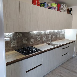 Rovná kuchyňská linka na míru s dvířky v dekoru Whitewood, pracovní deskou v dekoru Dub Halifax cínový a zádovým panelem v dekoru Ornamentic Wood.