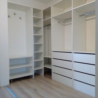 Šatna v bílém dekoru se zásuvkami a posuvnými dveřmi.